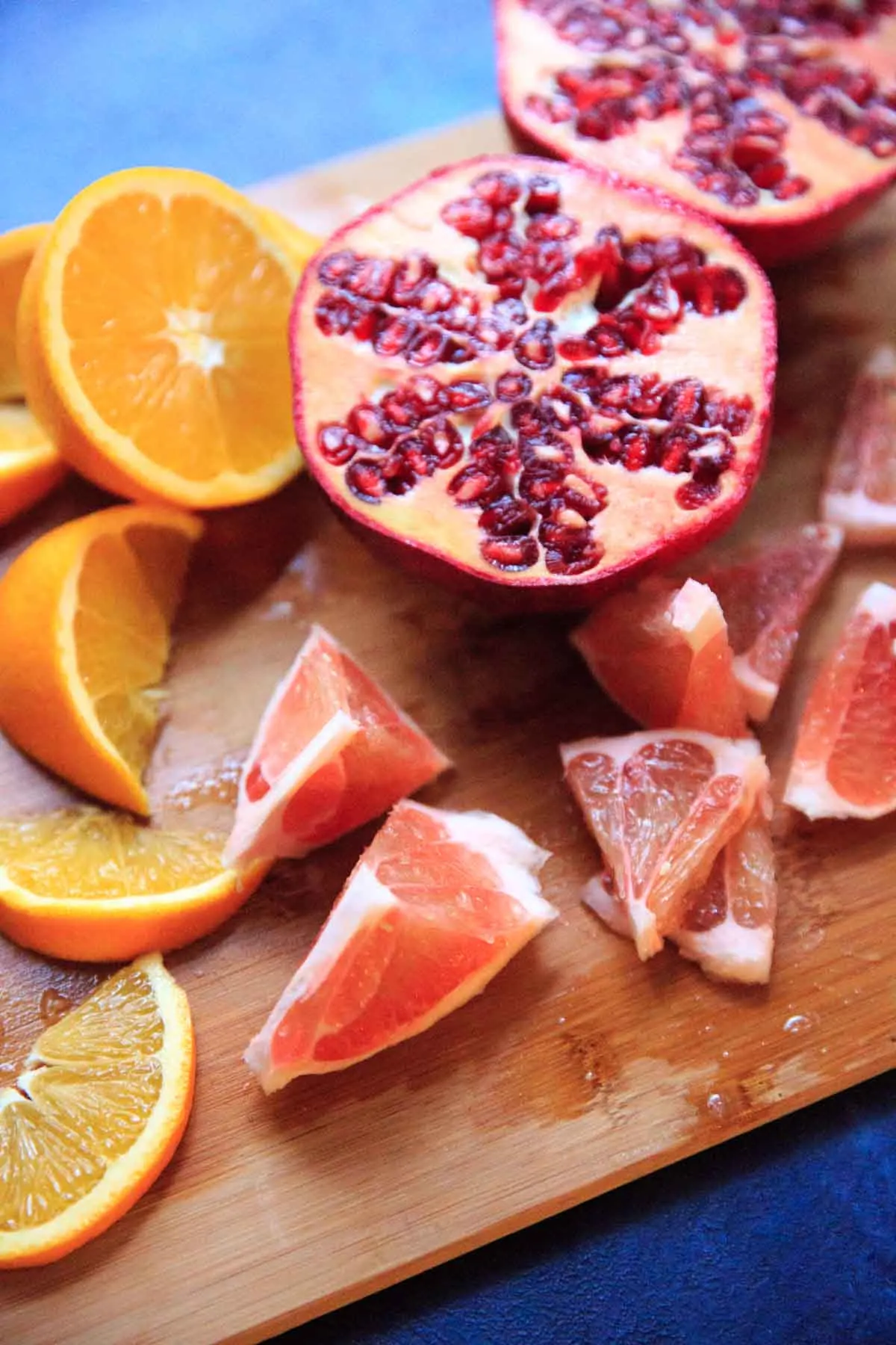 cut up oranges, pomegranate and pomelo pieces on cutting board