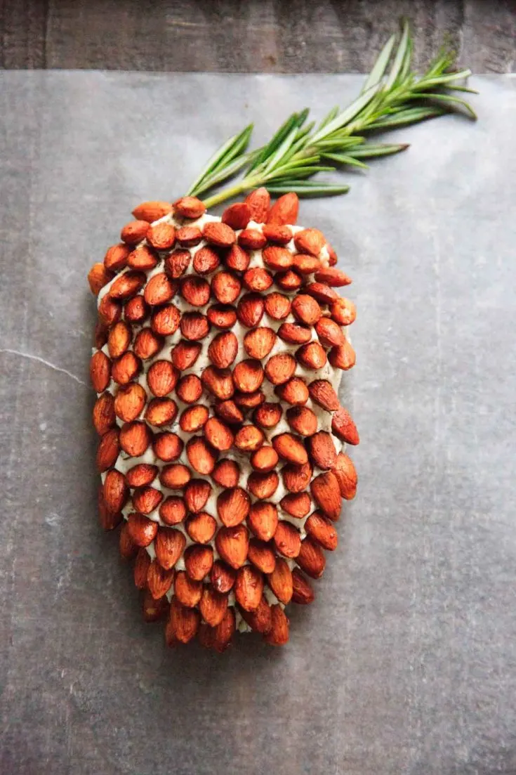 A cheese ball that looks like a pine cone! This will be a hit at your party. Using rosemary sprigs and cinnamon honey roasted almonds.