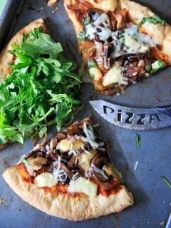 Homemade pizza with caramelized onions, fresh baby arugula and brie cheese!