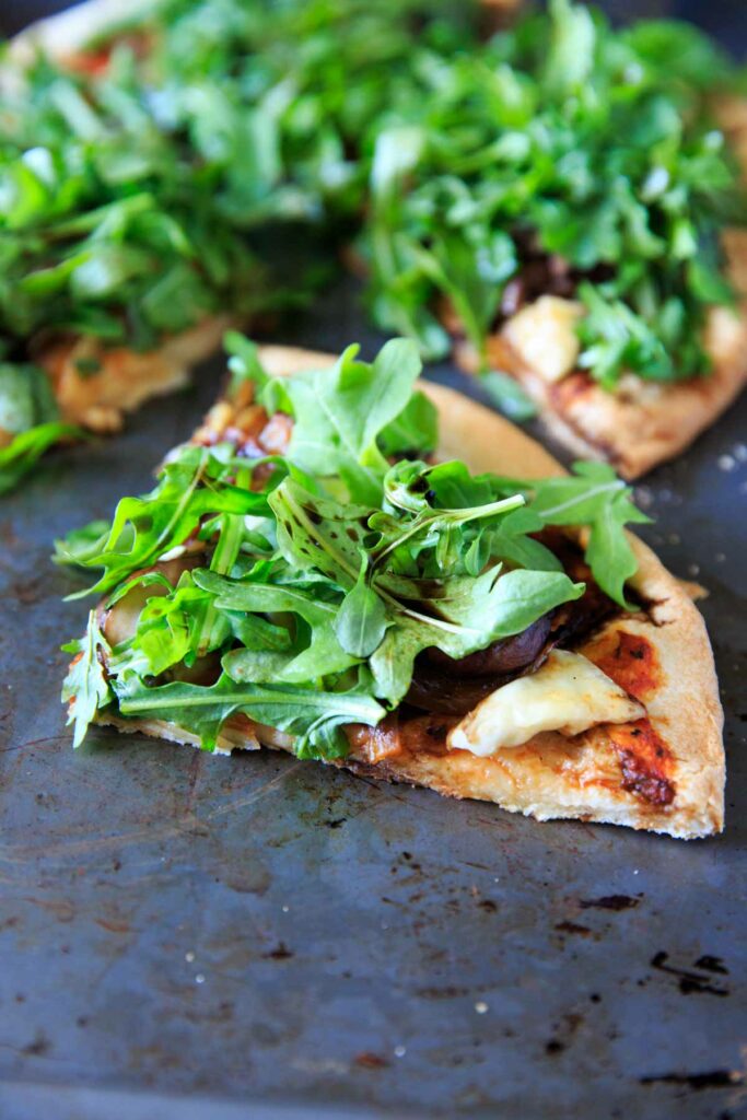 Homemade pizza with caramelized onions, mushrooms, fresh baby arugula and brie cheese! 