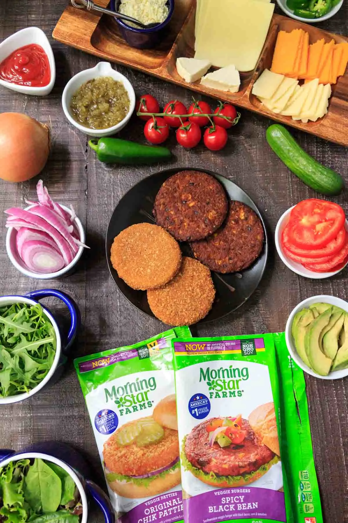 MorningStar vegetarian burger patties on black plate with veggies and cheese plate surrounding