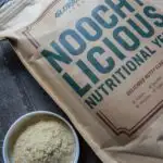 Noochy Licious nutritional yeast bags with some yeast flakes poured into a container