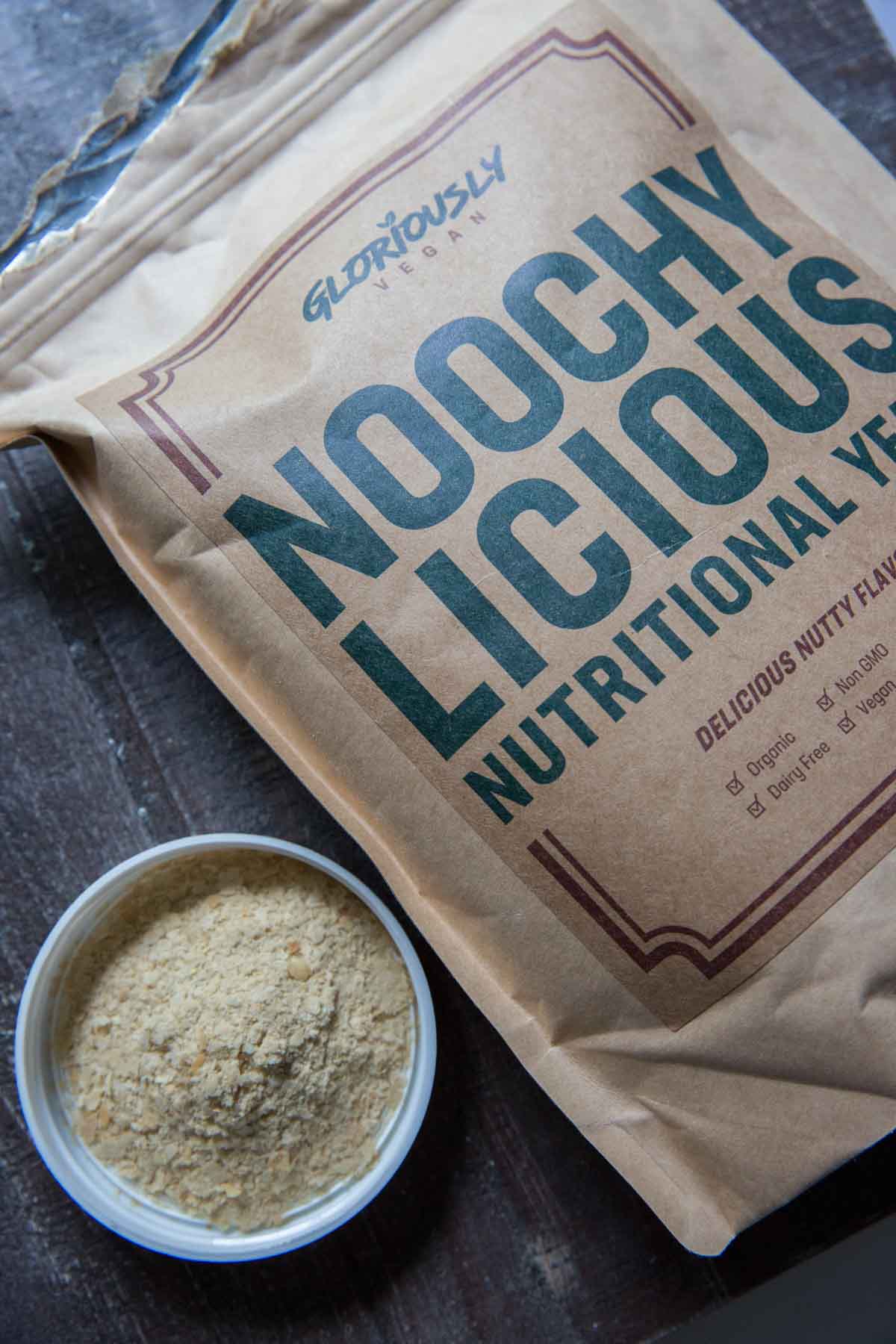 Noochy Licious nutritional yeast bags with some yeast flakes poured into a container