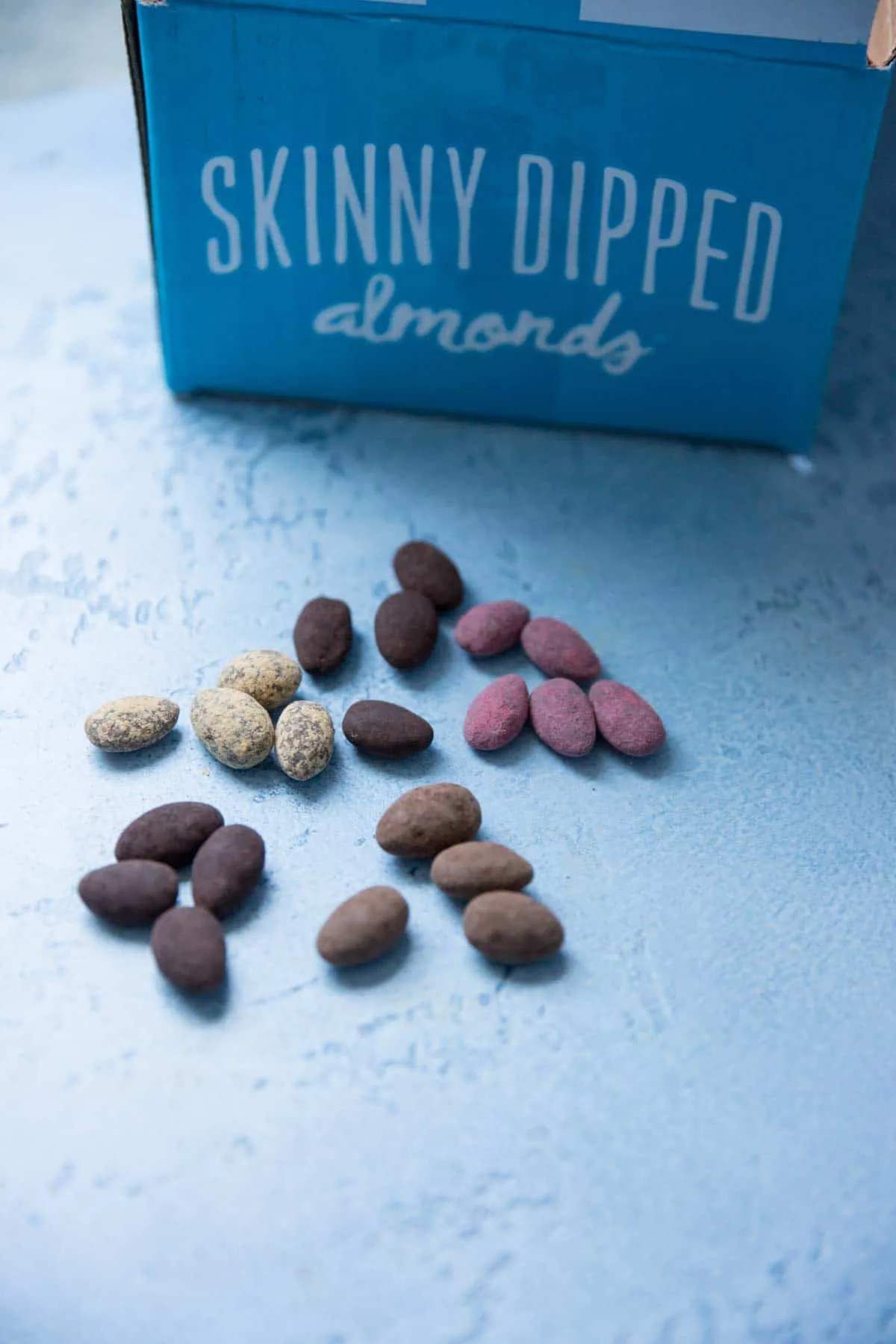 an assortment of skinny dipped almond flavors on blue background