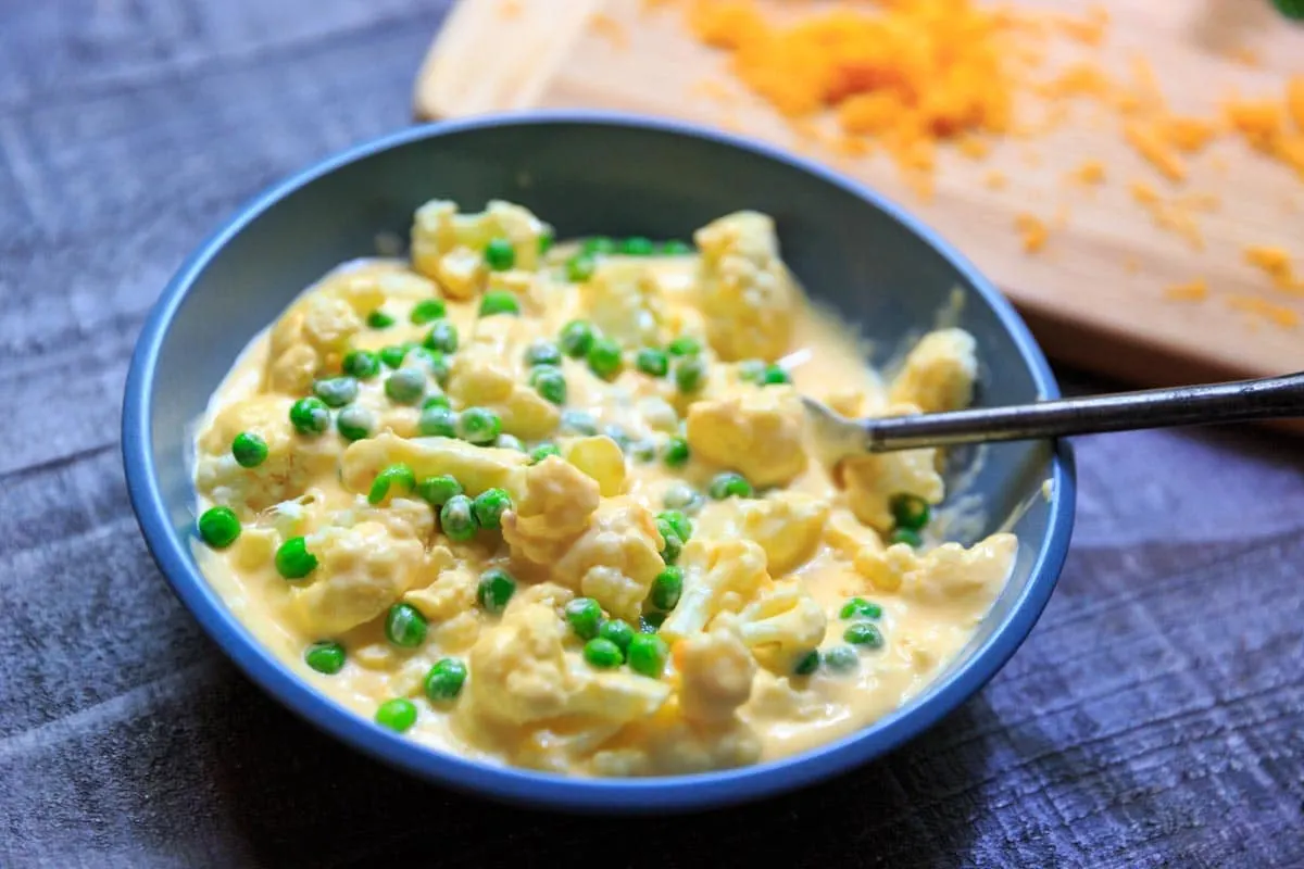 cheesy cauliflower florets with peas in bowl