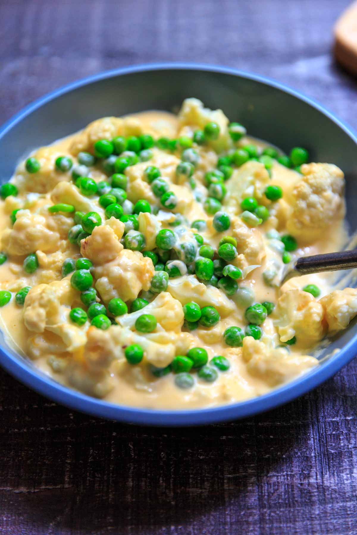 cheesy cauliflower florets with peas in bowl