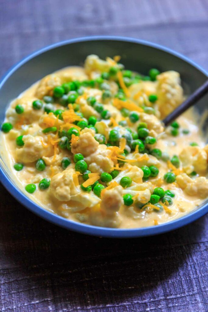 cheesy cauliflower florets with peas in bowl
