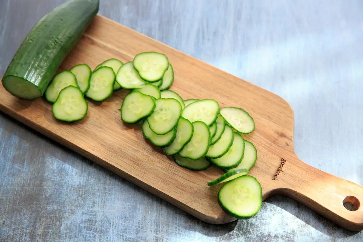 cut up cucumber slices on a cutting board for spa water