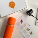 Vejo orange portable blender pictured with battery, immunity fuel pods and starter pack flavor info card
