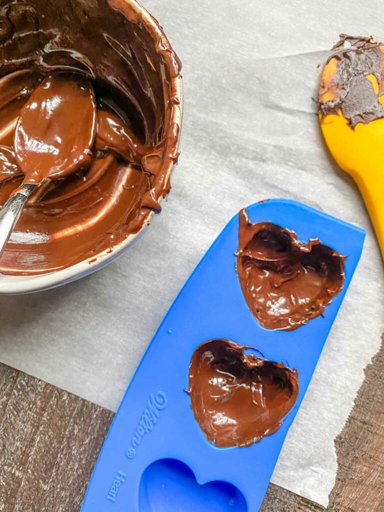 melted chocolate in heart-shaped silicone molds for DIY hot cocoa bombs