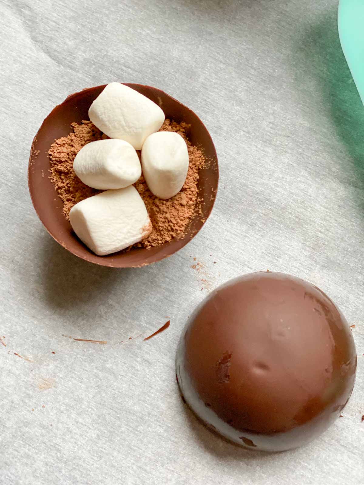 half of hot chocolate bomb filled with cocoa mix and mini vegan marshmallows, before combining two halves