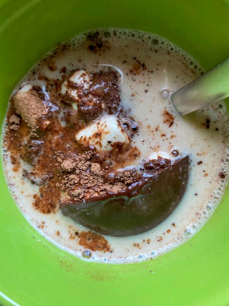 hot cocoa bomb exploding in mug of hot oat milk