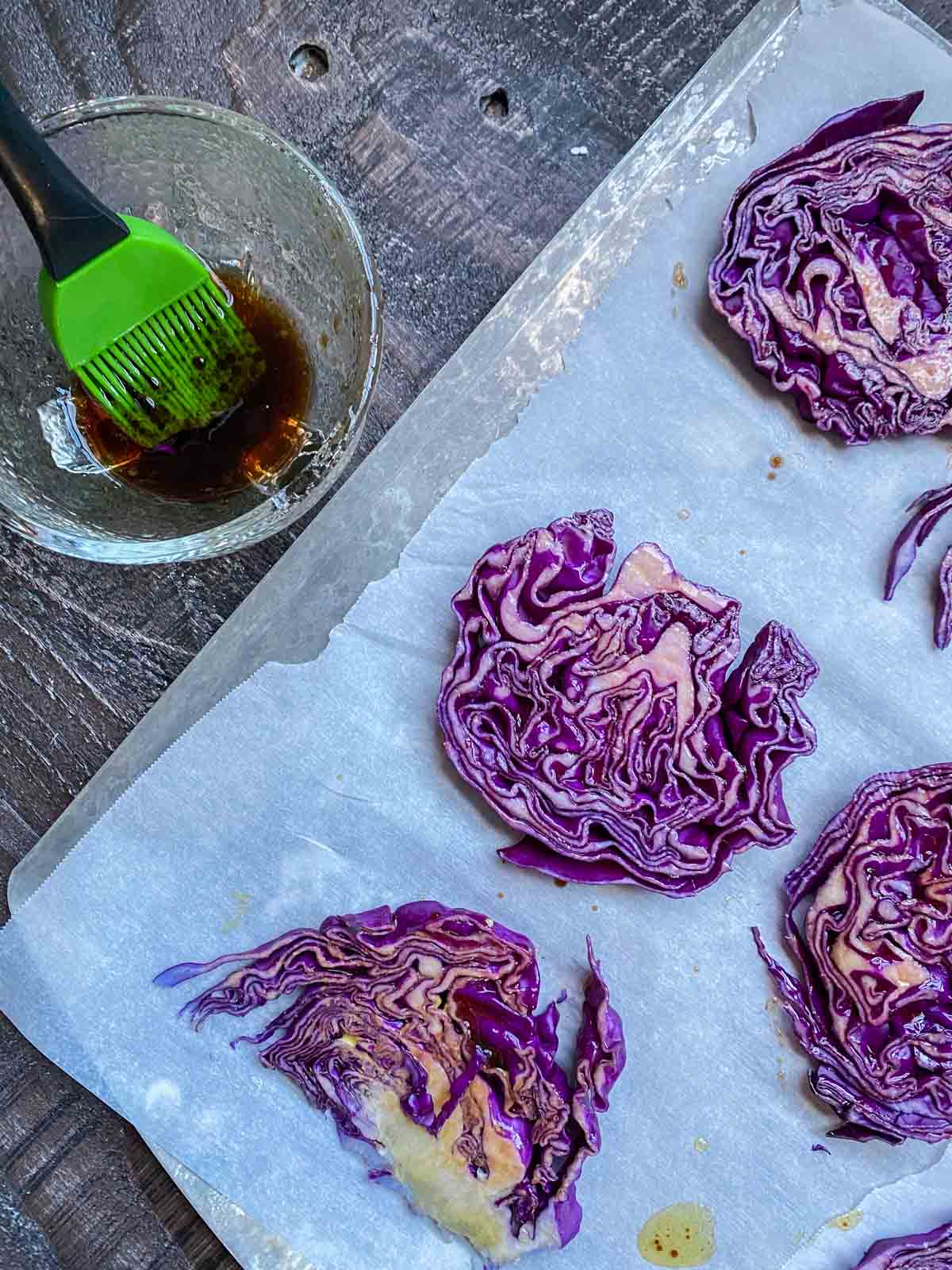 sliced cabbage steaks of cookie sheet with bowl of balsamic