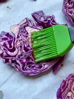 brushing on balsamic vinegar to a slice of red cabbage steaks