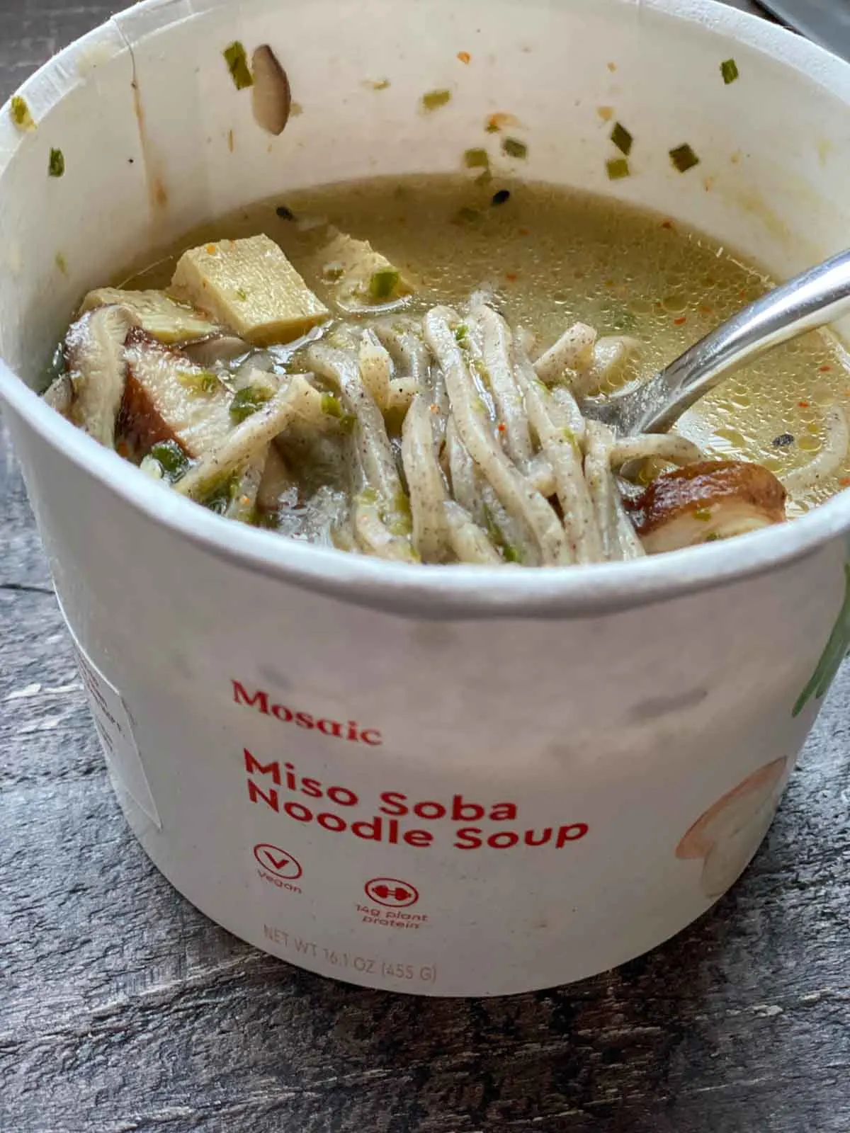 mosaic foods miso soba noodle vegan soup, cooked showing a spoonful out of the cup