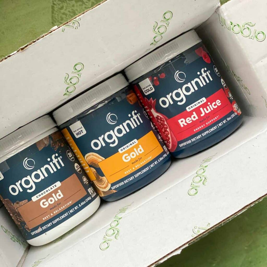 3 jars of organifi powder in box, chocolate gold, original gold, red juice