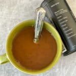 mud water in green mug with spoon next to labeled container