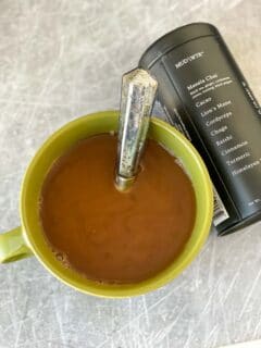 mud water in green mug with spoon next to labeled container