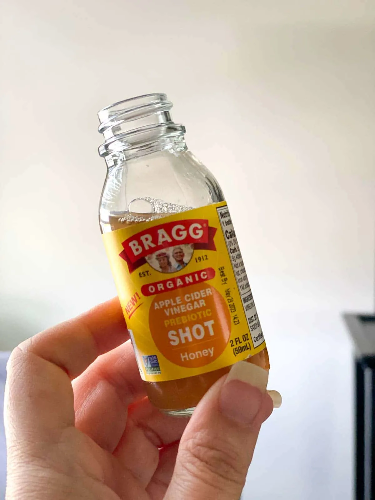 holding shot of bragg apple cider vinegar with honey