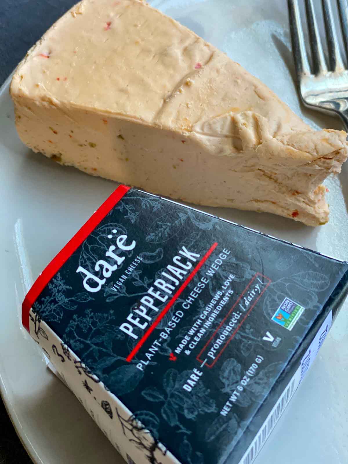 a fork next to a wedge of pepperjack darë vegan cheese