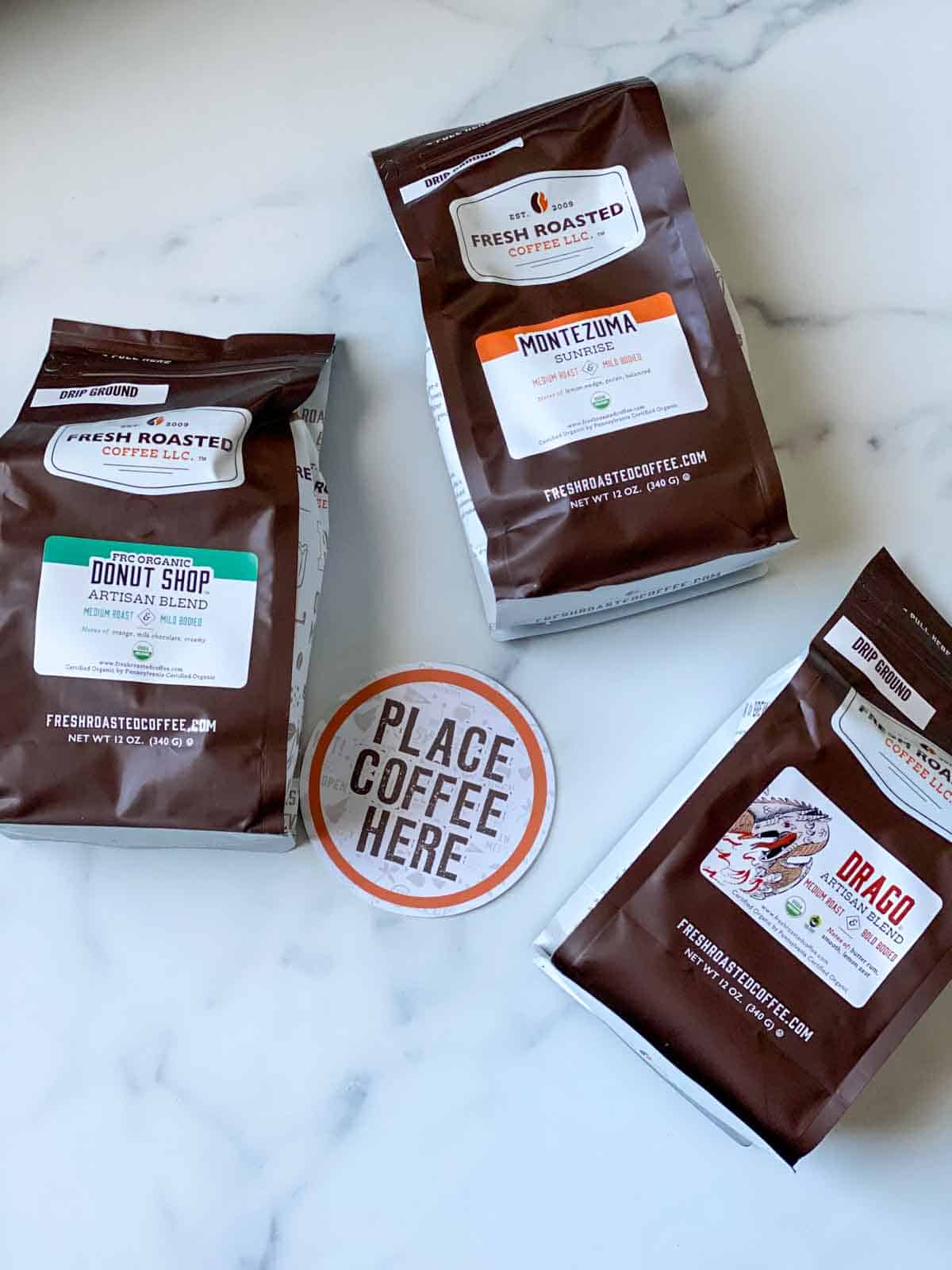 3 bags of fresh roasted coffee LLC with a "place coffee here" drink holder