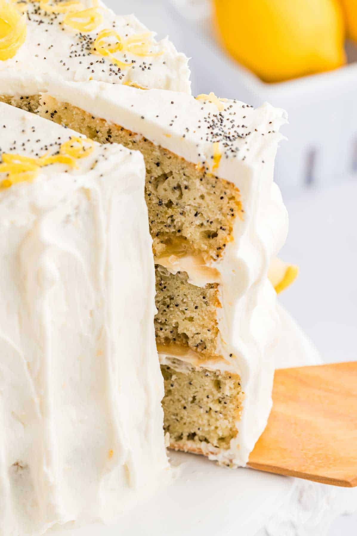 cutting a slice of the 3-layered lemon poppyseed cake.