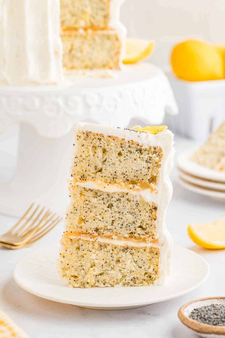 a slice of the 3-layer lemon poppyseed cake on a plate.