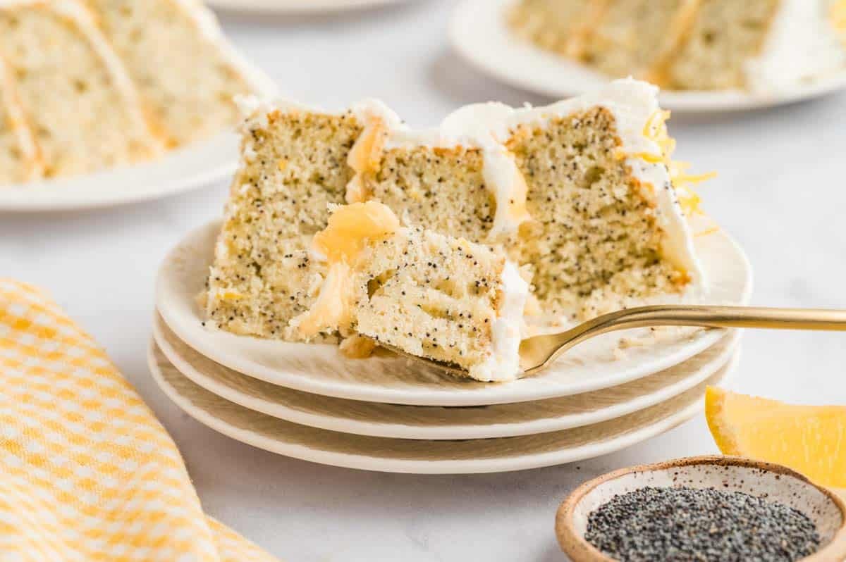 a slice of the 3-layer lemon poppyseed cake on a plate with a bite on the fork.