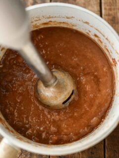 immersion blender in pot of apple butter making the texture smooth.